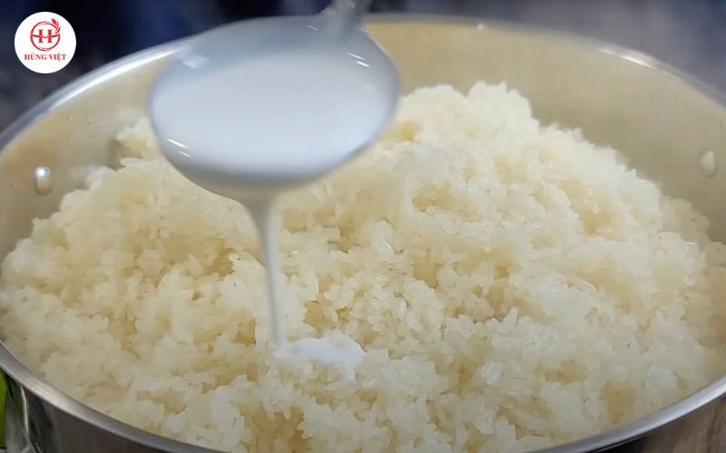 Trộn xôi với nước cốt dừa sau khi hấp lần 1