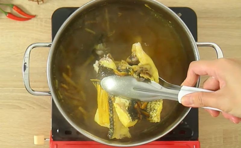 Vớt cá lóc đã luộc ra khỏi nồi nước dùng bún cá