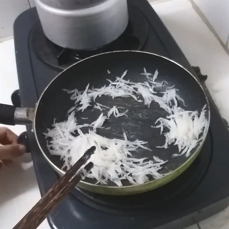 Xào dừa nạo sợi với đường trên chảo cho đến khi dừa trong lại, sẵn sàng làm xôi dừa hạt sen.