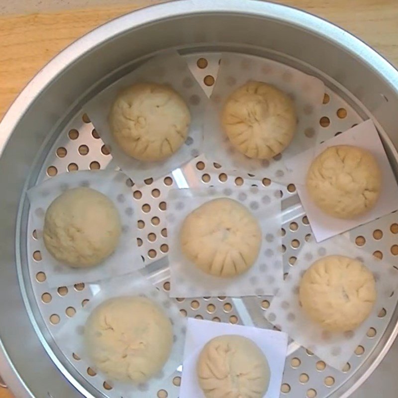 Xếp bánh bao đã tạo hình vào xửng hấp có lót giấy nến, chuẩn bị hấp chín bánh bao bằng bột mì và bột nở.