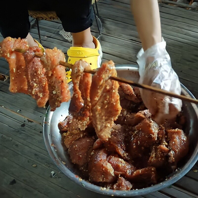 Xiên từng miếng thịt heo đã ướp vào thanh nứa để chuẩn bị gác bếp