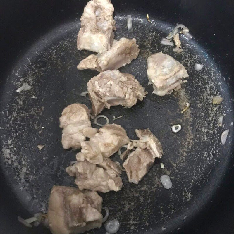 Xương heo và rau củ đang được xào trên bếp để chuẩn bị cách nấu canh rau củ