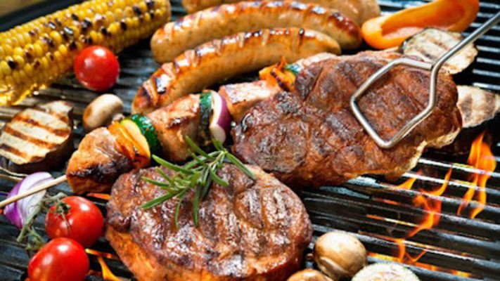 Bàn tiệc đồ nướng hấp dẫn với nhiều loại thịt, rau củ và chén nước chấm, minh họa lượng calo trong đồ nướng.