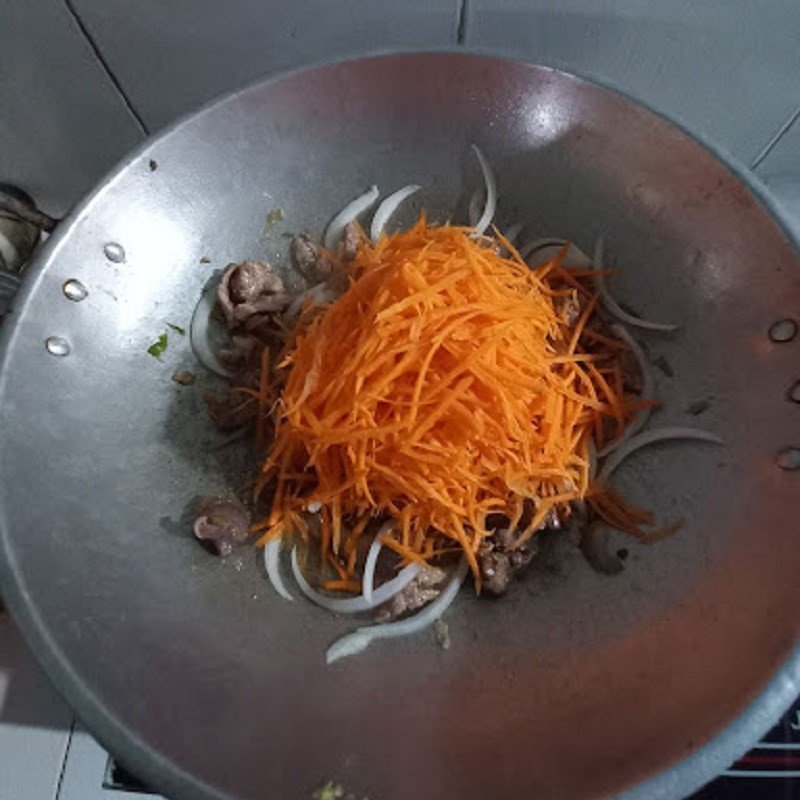 Các loại rau củ như cà rốt, hành tây, giá đỗ được thêm vào chảo xào cùng thịt