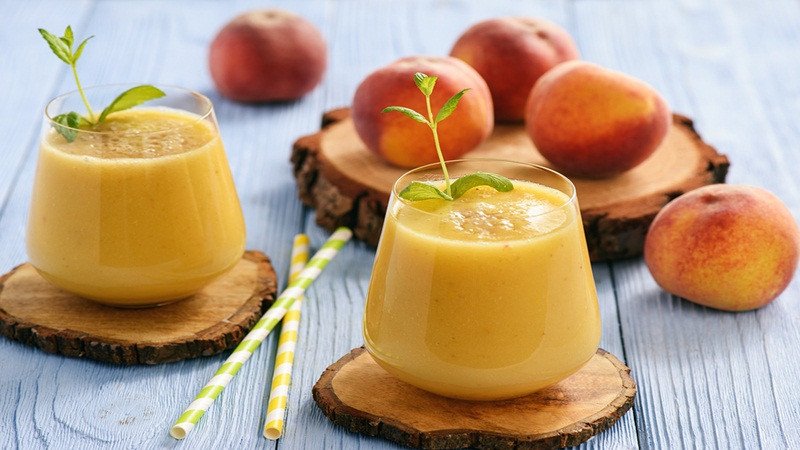 Ly sinh tố đào mỏ quạ sánh mịn, trang trí bằng lát đào và lá bạc hà, một cách thưởng thức đào mỏ quạ lành mạnh.
