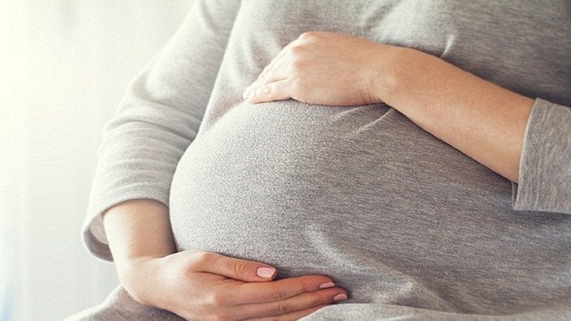 Một phụ nữ mang thai đang chạm vào bụng, thể hiện mối quan tâm liệu phụ nữ có thai có nên ăn đào mỏ quạ.