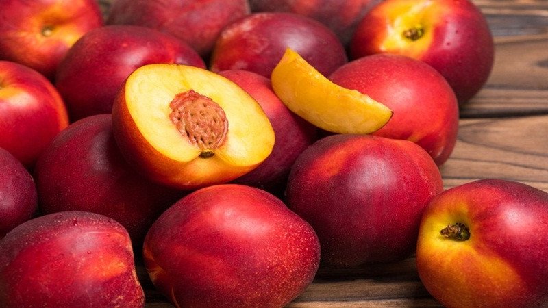 Một quả đào mỏ quạ được cắt lát, nằm trên chiếc đĩa trắng, thể hiện câu hỏi ăn đào mỏ quạ có béo không.