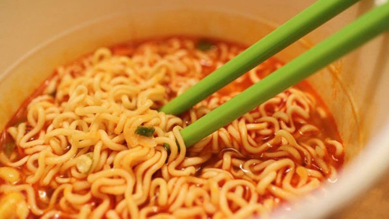 Một thìa nhỏ muối trên nền bát mì tôm, nhấn mạnh hàm lượng natri cao trong mì gói