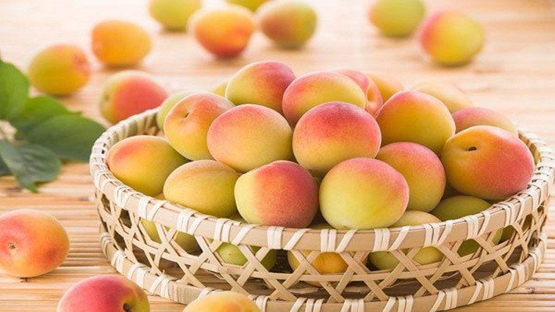 Nhiều quả đào mỏ quạ tươi trên bàn gỗ, nhắc nhở về những lưu ý khi ăn đào mỏ quạ.